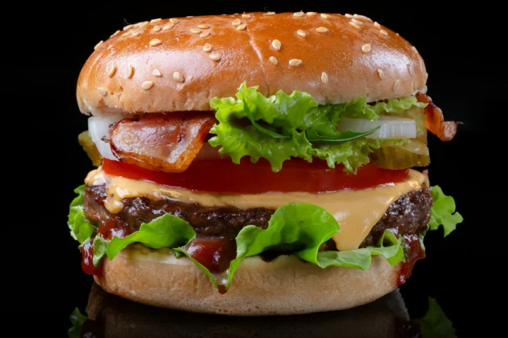 Classic burger with cheese, tomato and lettuce on a dark background