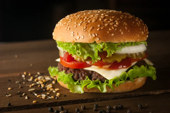 Sesame bun burger with fresh vegetables on a wooden table