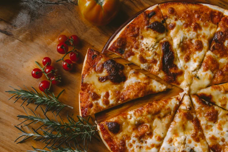 Sliced cheese pizza on a wooden board with tomatoes and herbs