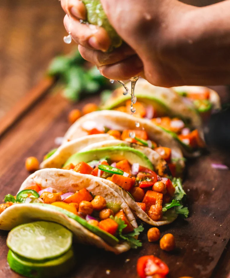 Row of tacos topped with fresh salsa and herbs